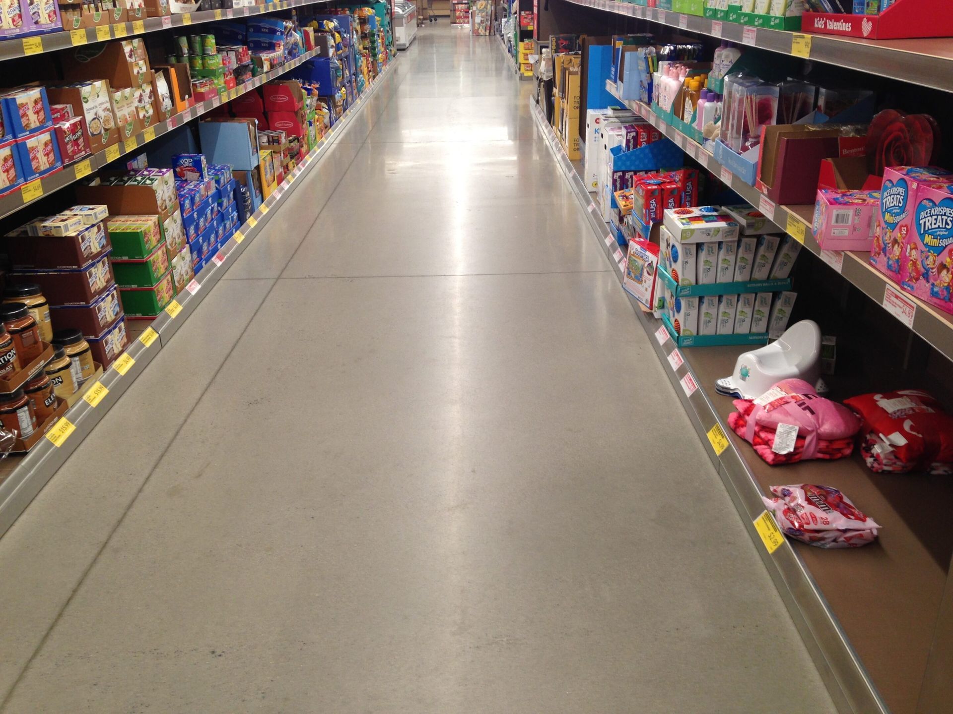 A grocery store aisle with shelves of colorful products on both sides and items scattered on the floor.