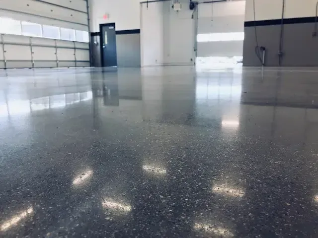 Empty polished garage with gray floor and white walls, reflecting overhead lights