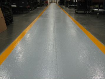 Empty factory aisle with gray floor and yellow edge lines