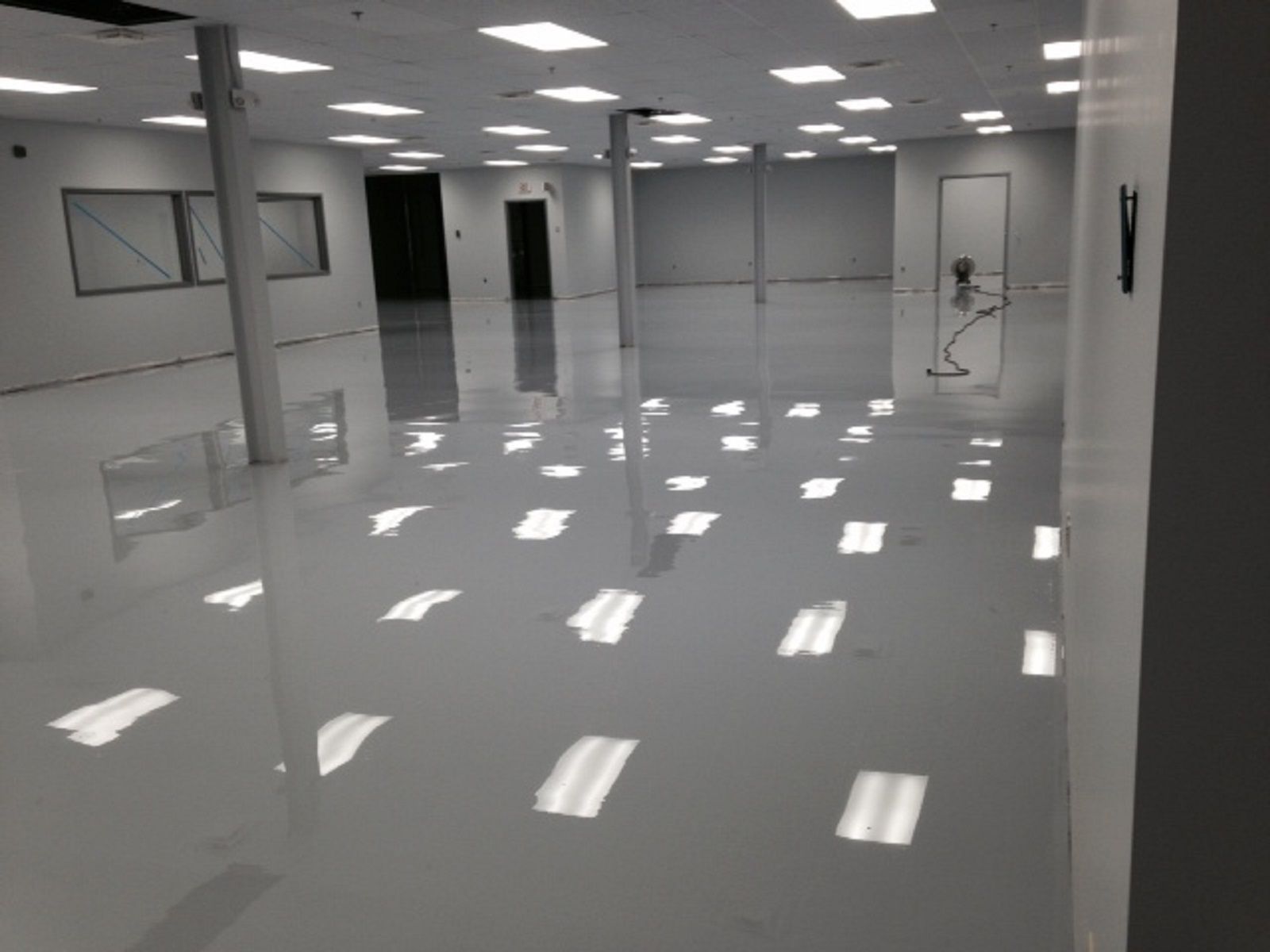 Empty polished room with glossy white floor, ceiling lights, and open doorways.