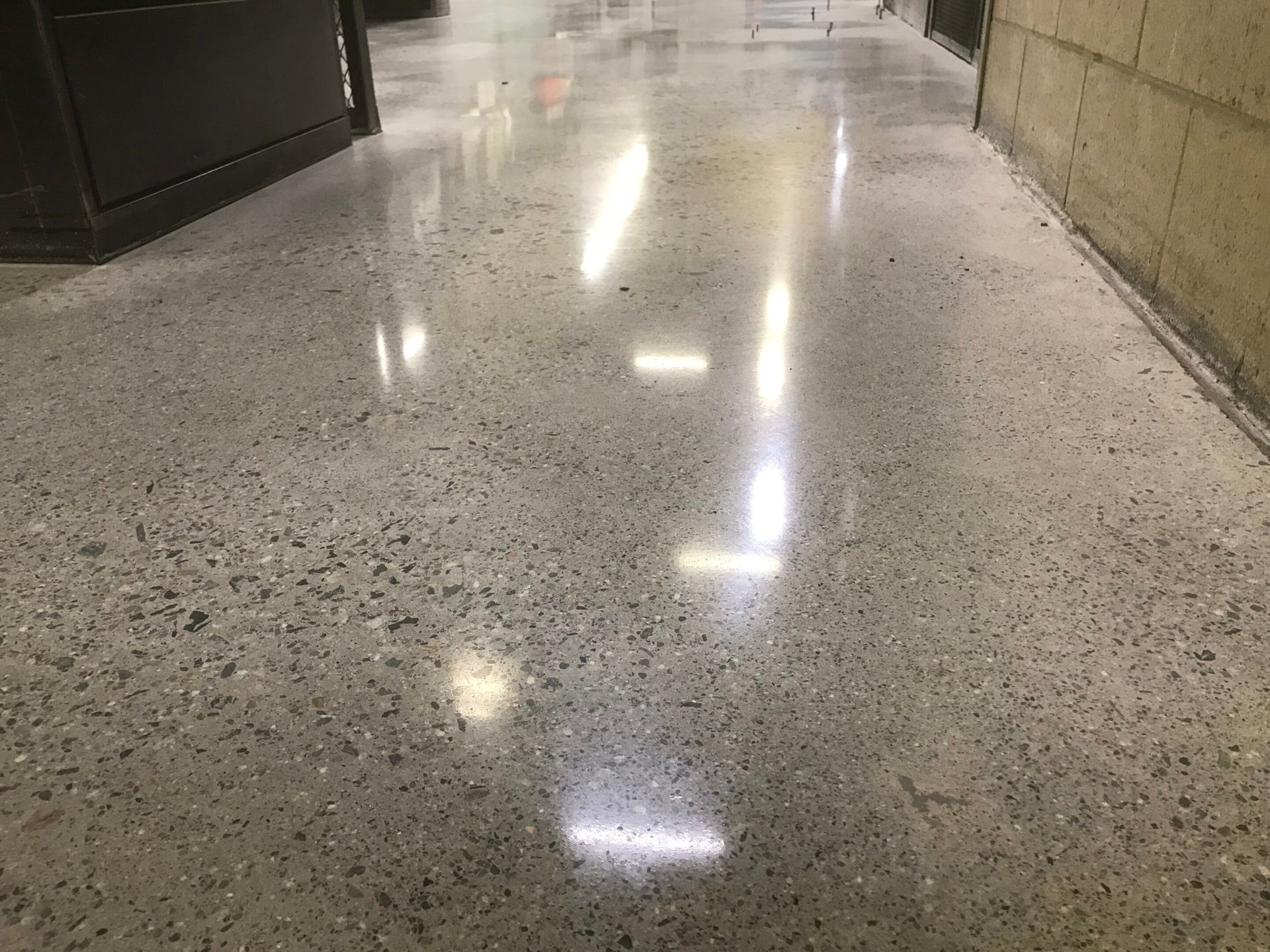 Shiny speckled terrazzo hallway floor reflecting overhead lights