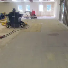 Empty room with carpet cleaning equipment and wet floor during renovation