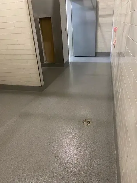 Empty tiled hallway with a doorway and elevator area in the background.