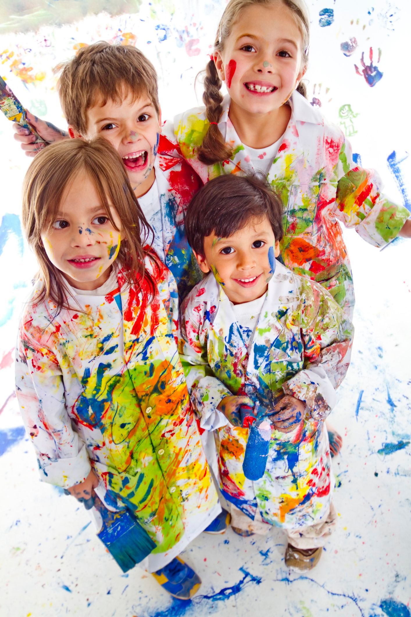 Two young girls are painting on a wall in a room.