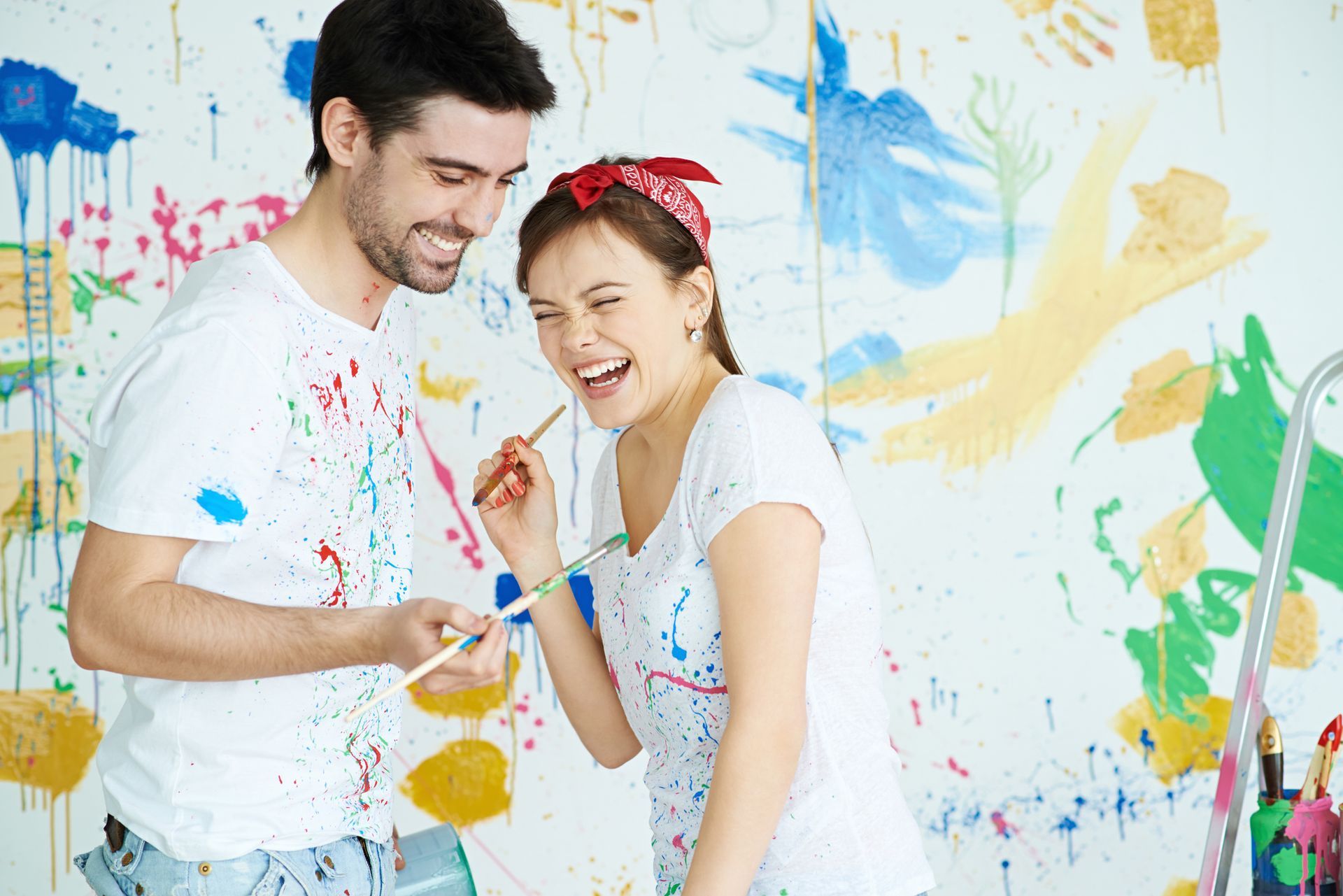 Two women are painting a picture on a wall in an art studio.