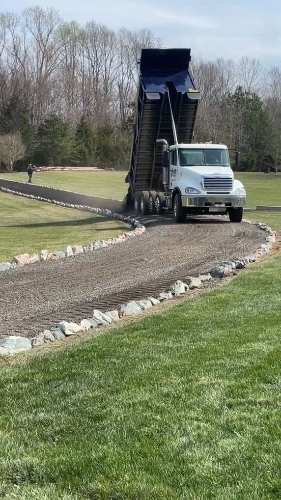 A dump truck is driving down a dirt road.