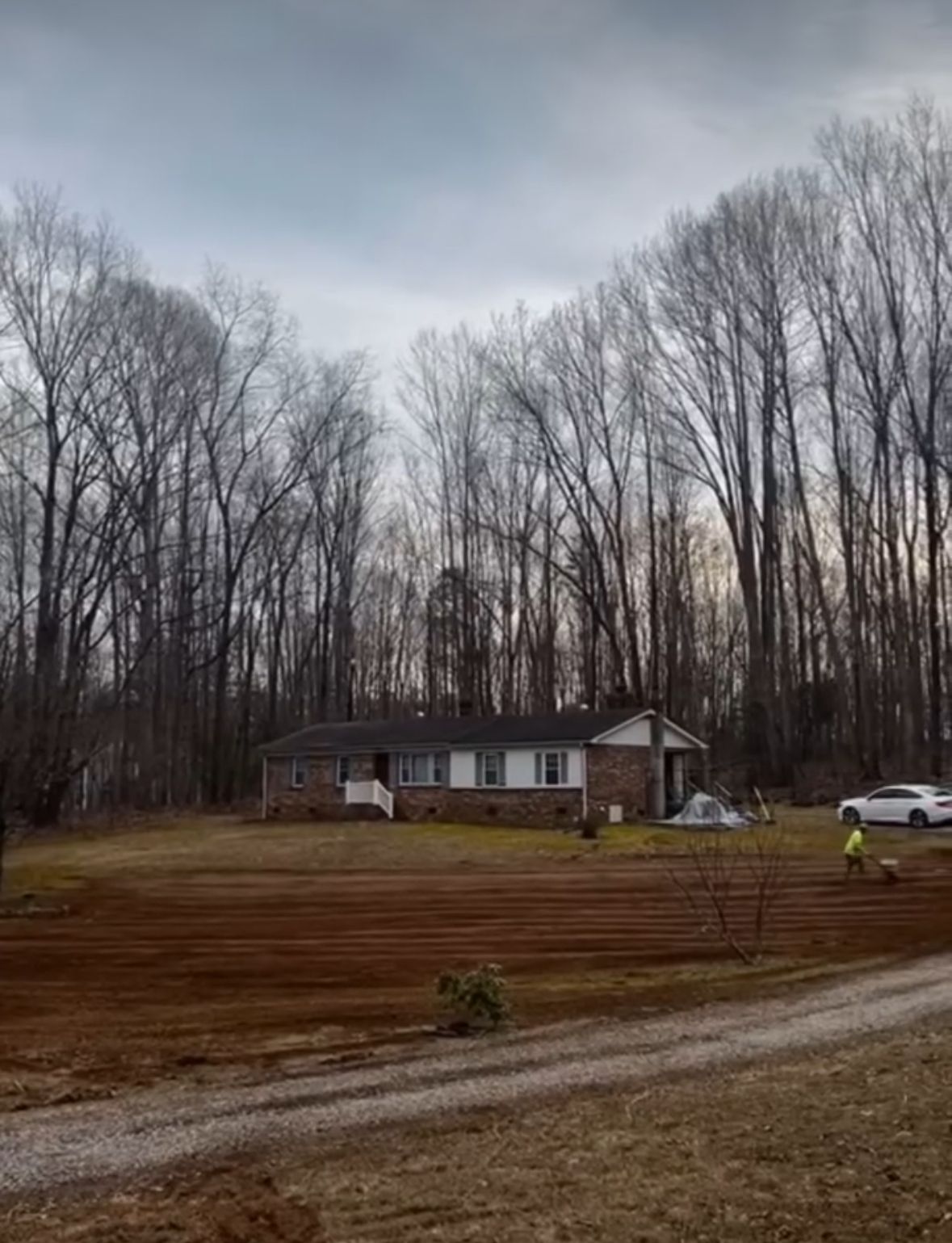 There is a house in the middle of a field with trees in the background.