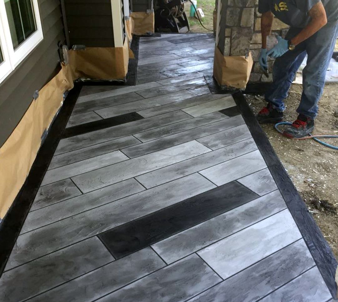 a man is working on a concrete walkway that looks like wood