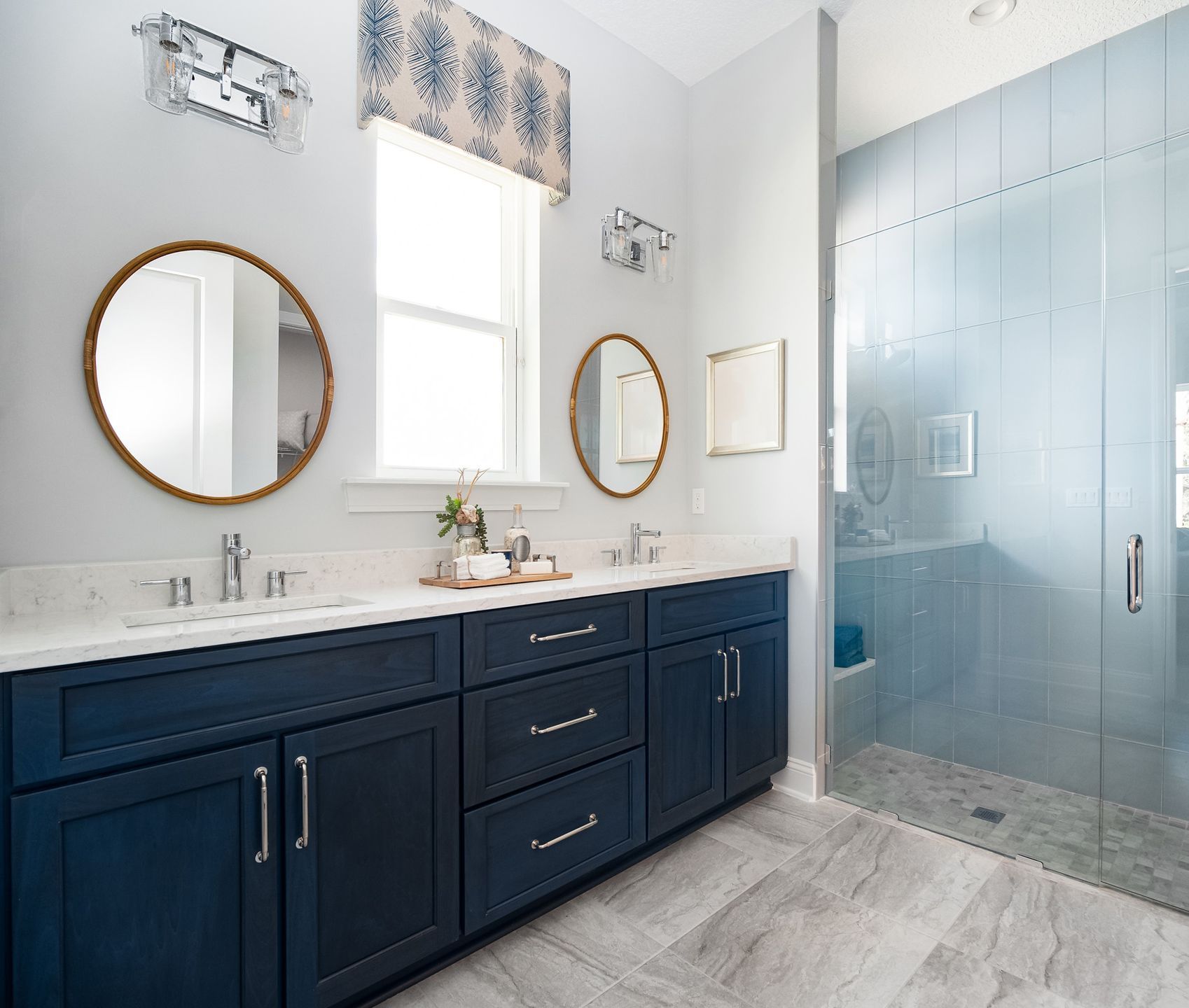 A bathroom with two sinks , two mirrors and a walk in shower.