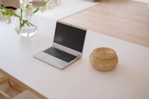 a Laptop Computer is Sitting on a White Table Next to a Vase of Flowers — The Home Assembly In Avoca Beach, NSW