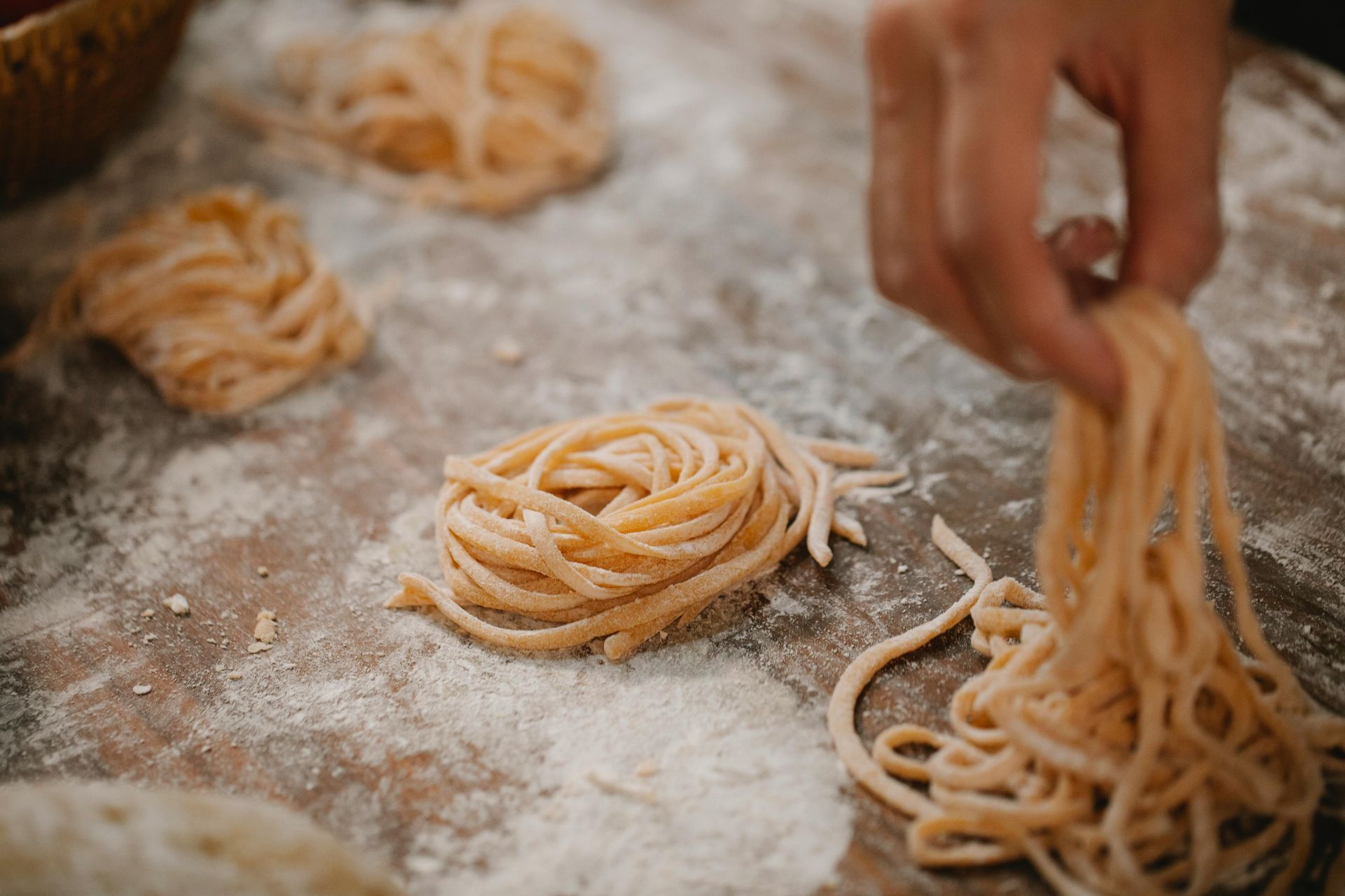 Persona che dispone i nidi di pasta appena fatti su una superficie infarinata.