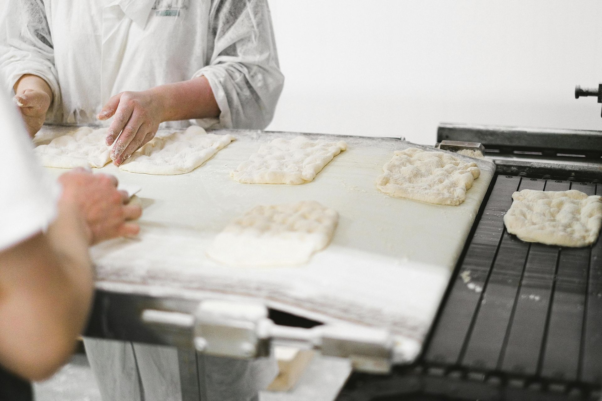 Lavoratori che modellano l'impasto su un nastro trasportatore in un panificio.