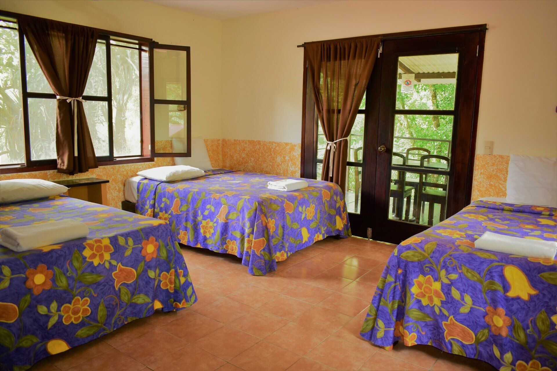 Una habitación de hotel con tres camas y balcón.