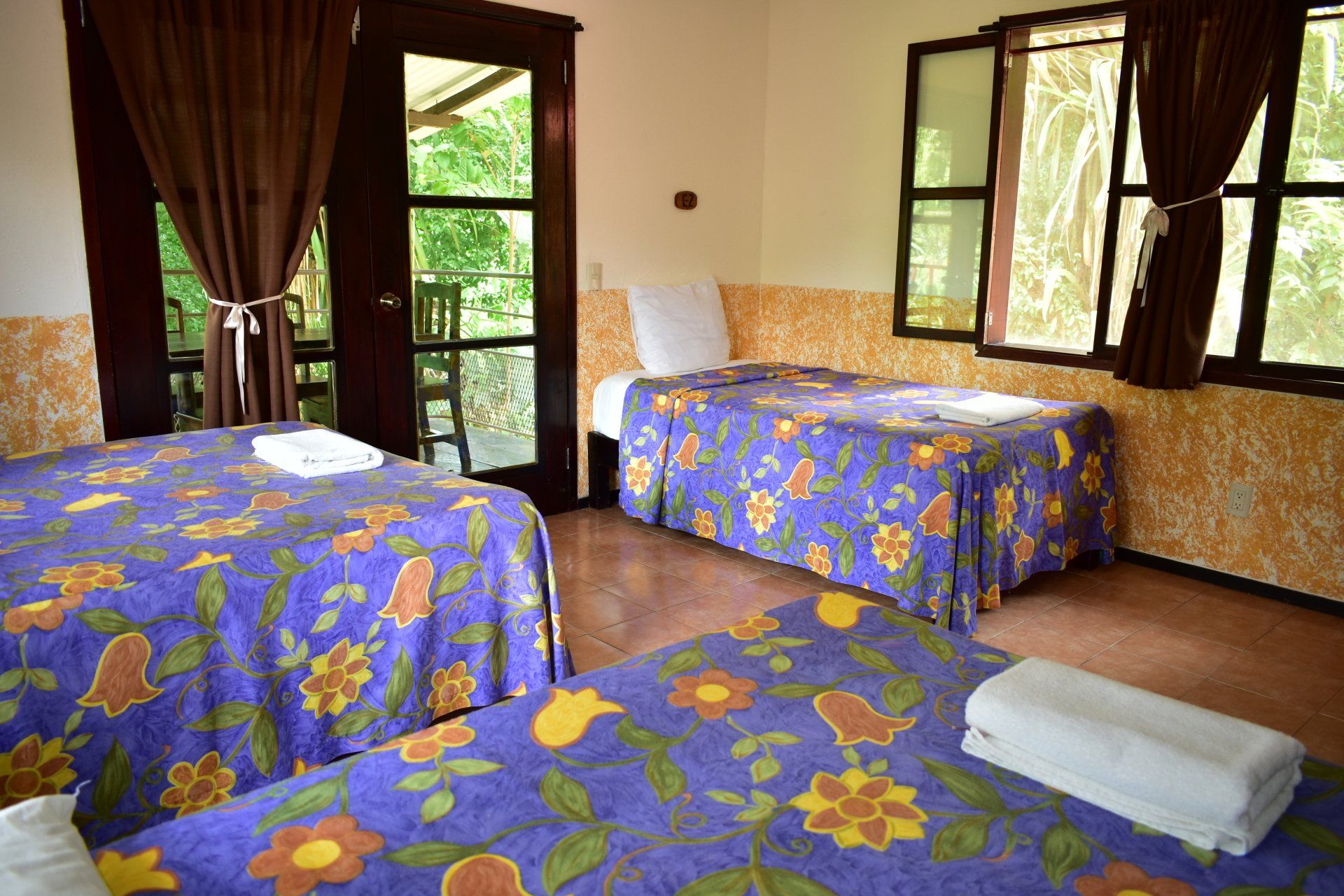 Una habitación de hotel con dos camas y balcón.