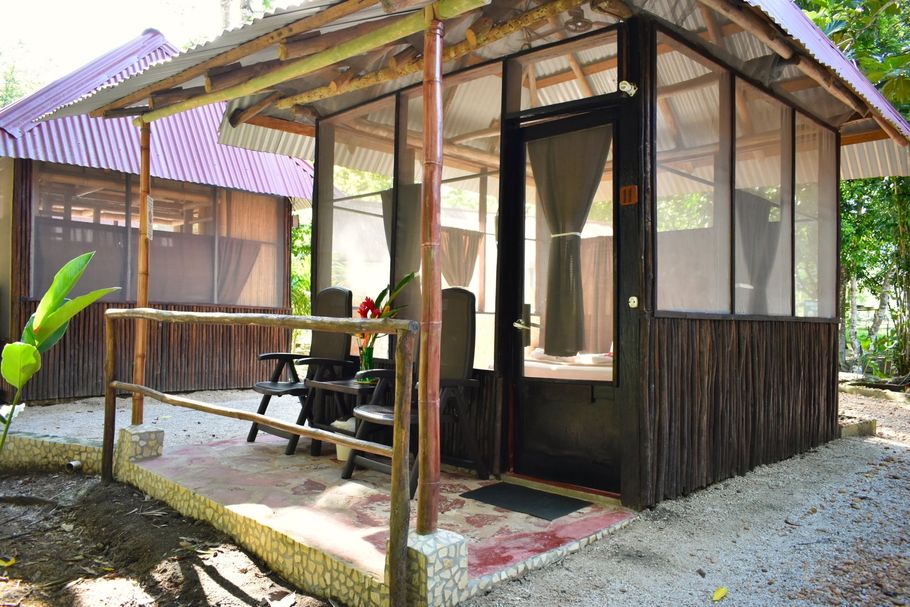 Una pequeña casa de madera con un porche cubierto y un techo morado.