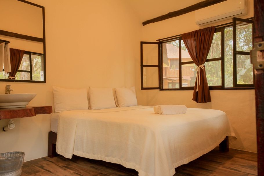 Un dormitorio con cama, lavabo, espejo y ventana.