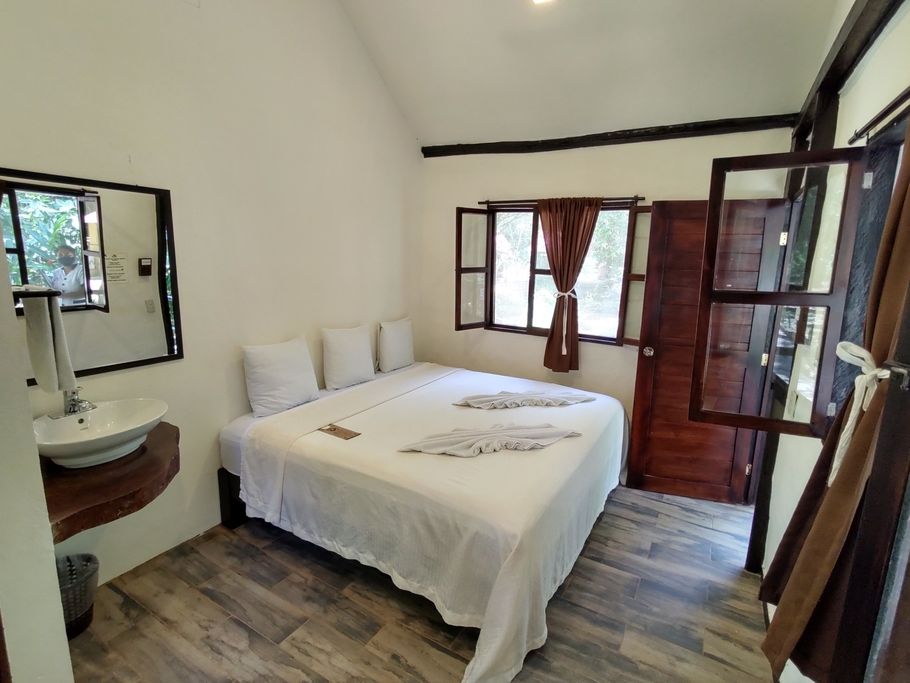 Un dormitorio con cama, lavabo, espejo y ventana.