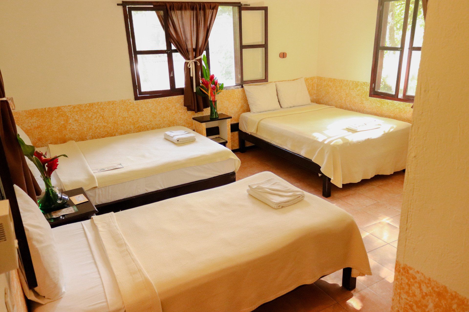 Una habitación de hotel con tres camas y dos ventanas.