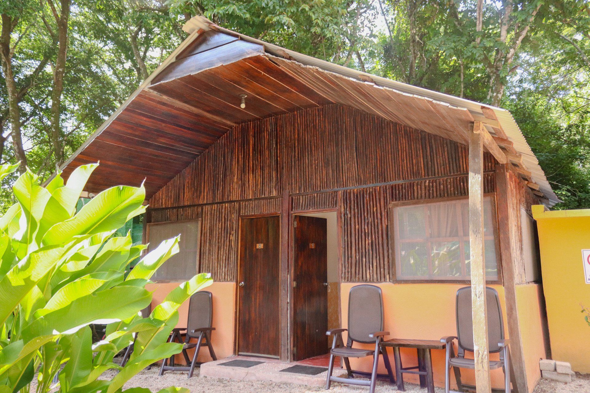 Una pequeña casa de madera con sillas y mesas delante de ella.