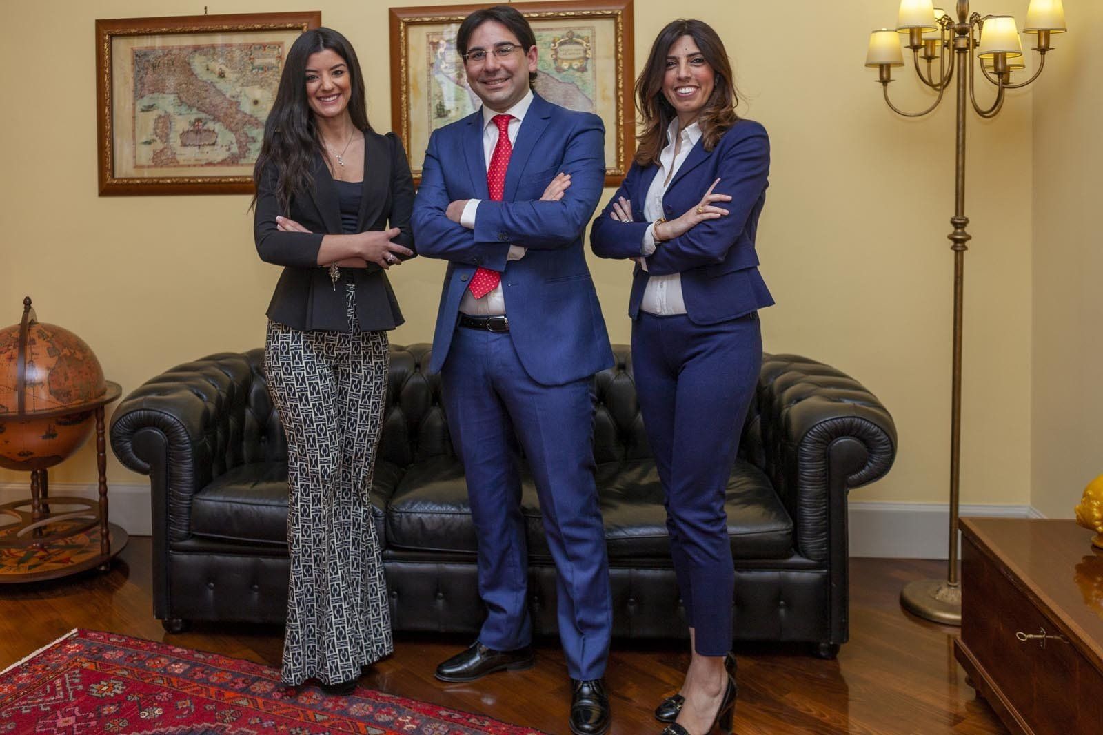 Tre professionisti in abiti da ufficio posano con sicurezza in un ambiente d'ufficio.