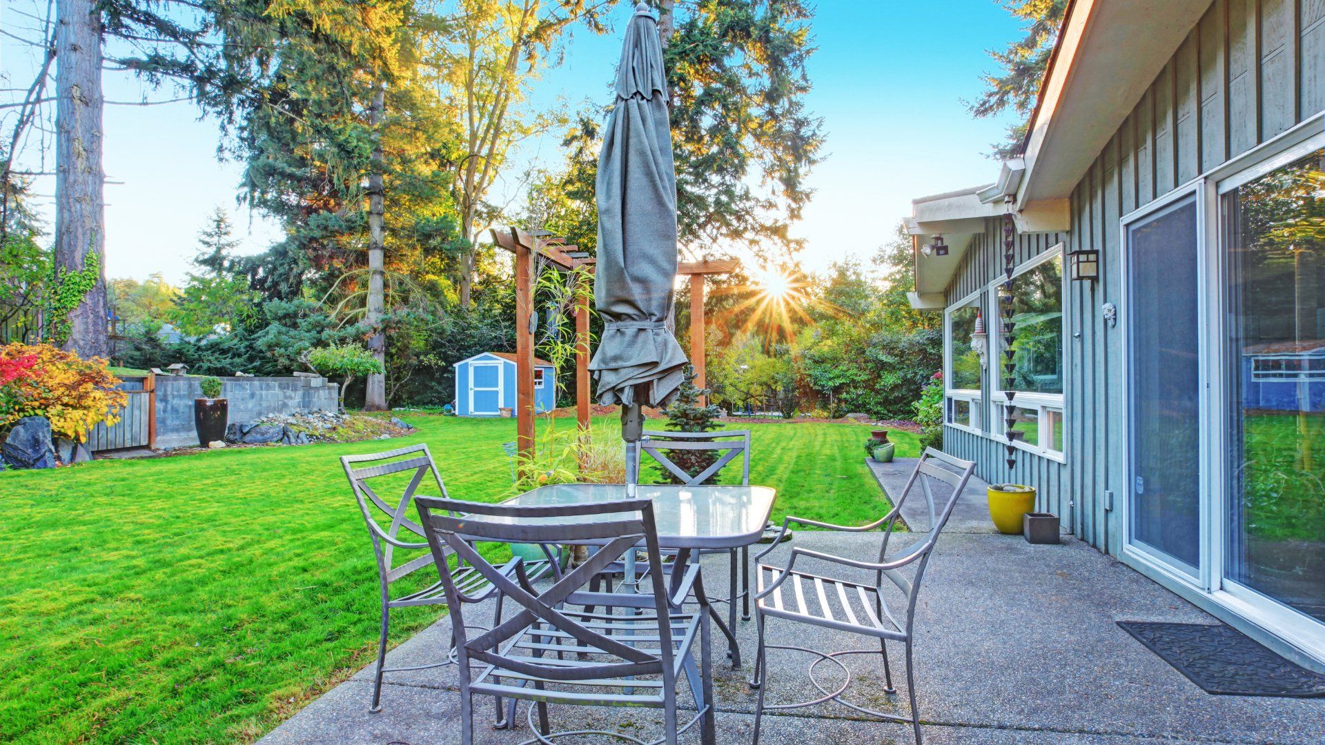 Small backyard concrete patio in Peterborough.  The patio looks out onto a grassy backyard with a shed and outdoor furniture.