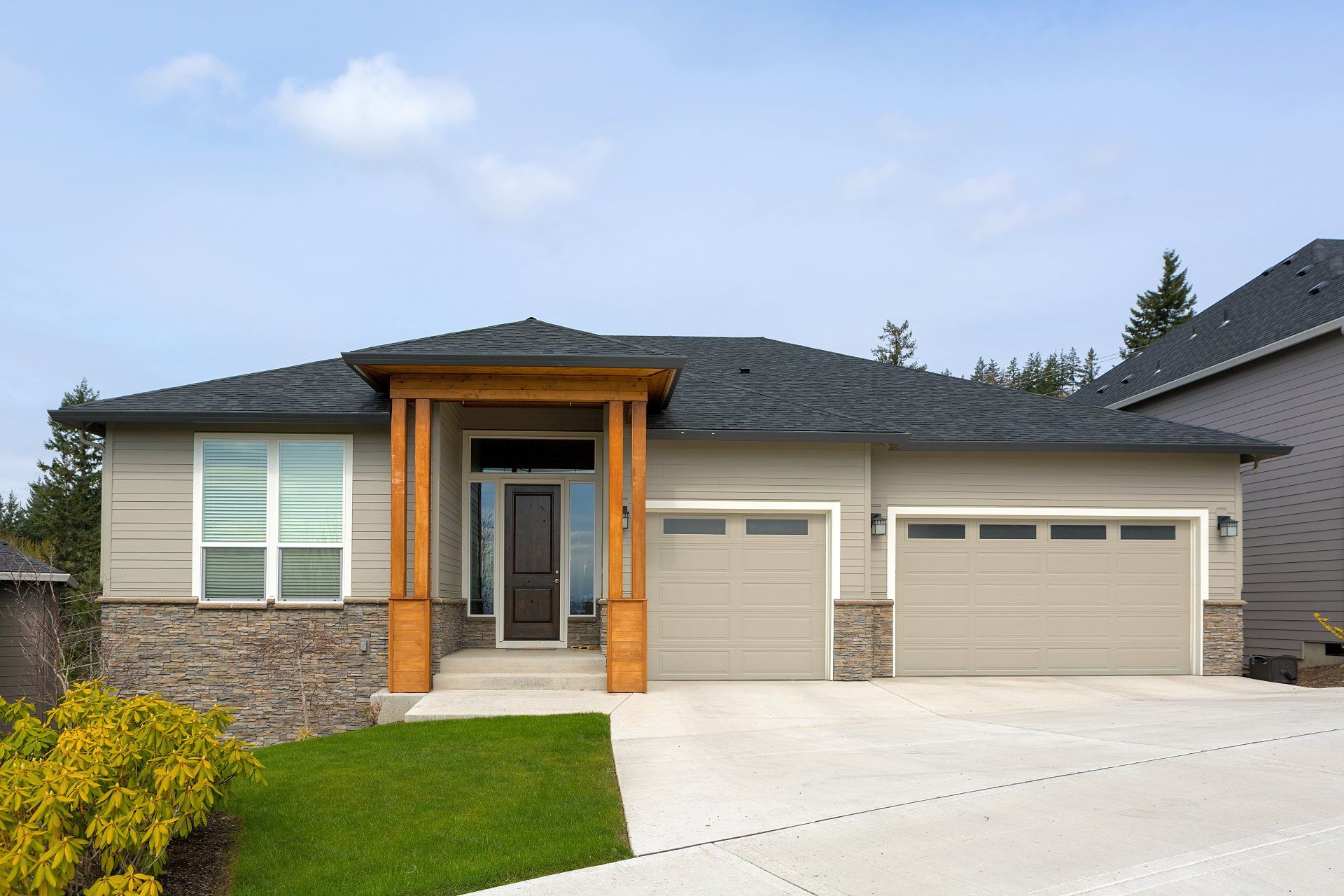 White concrete driveway leading up to two garage doors of a modern-looking bungalow in Peterborough.