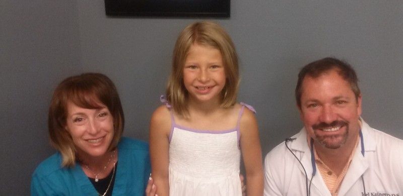 A little girl is posing for a picture with two doctors