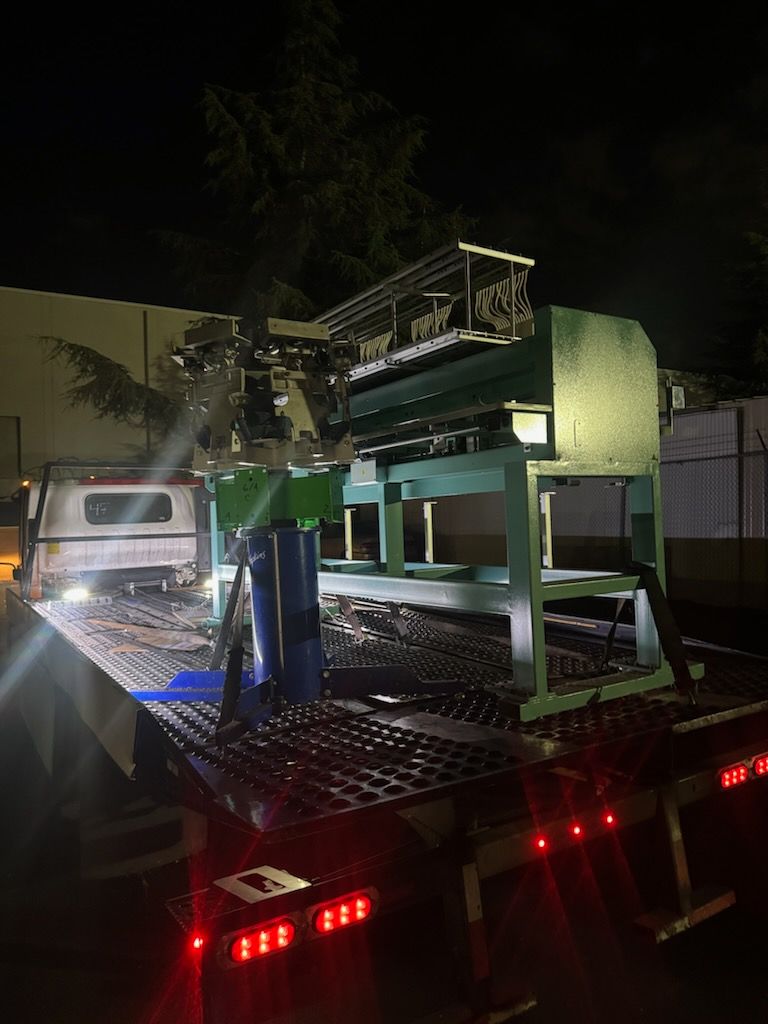 Industrial machine loaded and strapped on flatbed tow truck