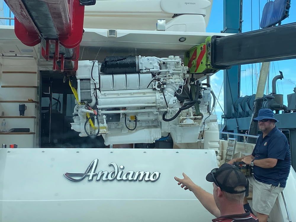 A Man is Pointing at a Large Engine on a Boat — Whitsunday Diesel & Marine In Mackay, QLD