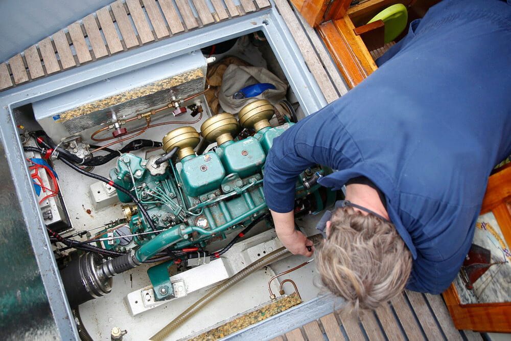 A Man is Working on the Engine of a Boat — Whitsunday Diesel & Marine In Ayr, QLD