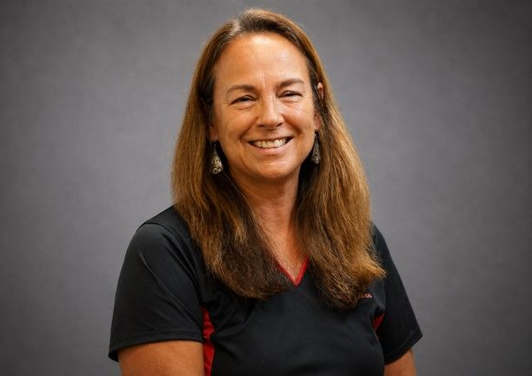 Smiling woman in a black shirt against a gray studio background