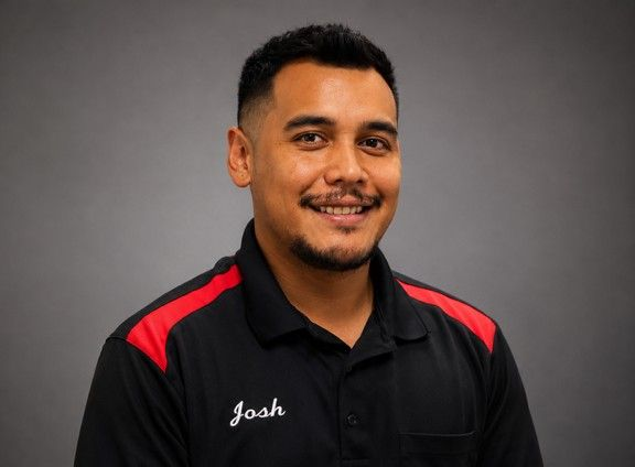 Smiling man in a black shirt with red shoulder stripes and the name “Josh” embroidered on it.