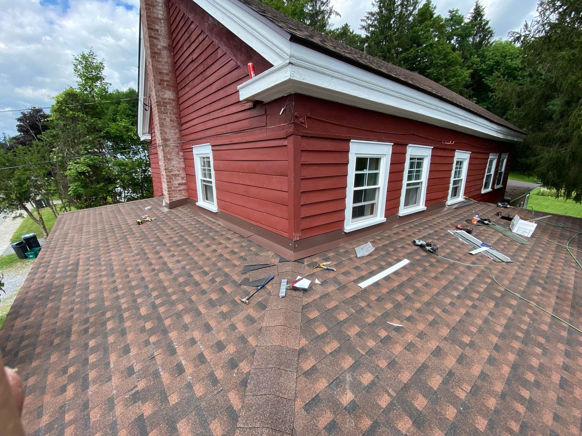 Red house roof with damaged shingles and scattered debris near the eaves