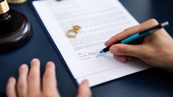 A person is writing on a piece of paper with a pen.