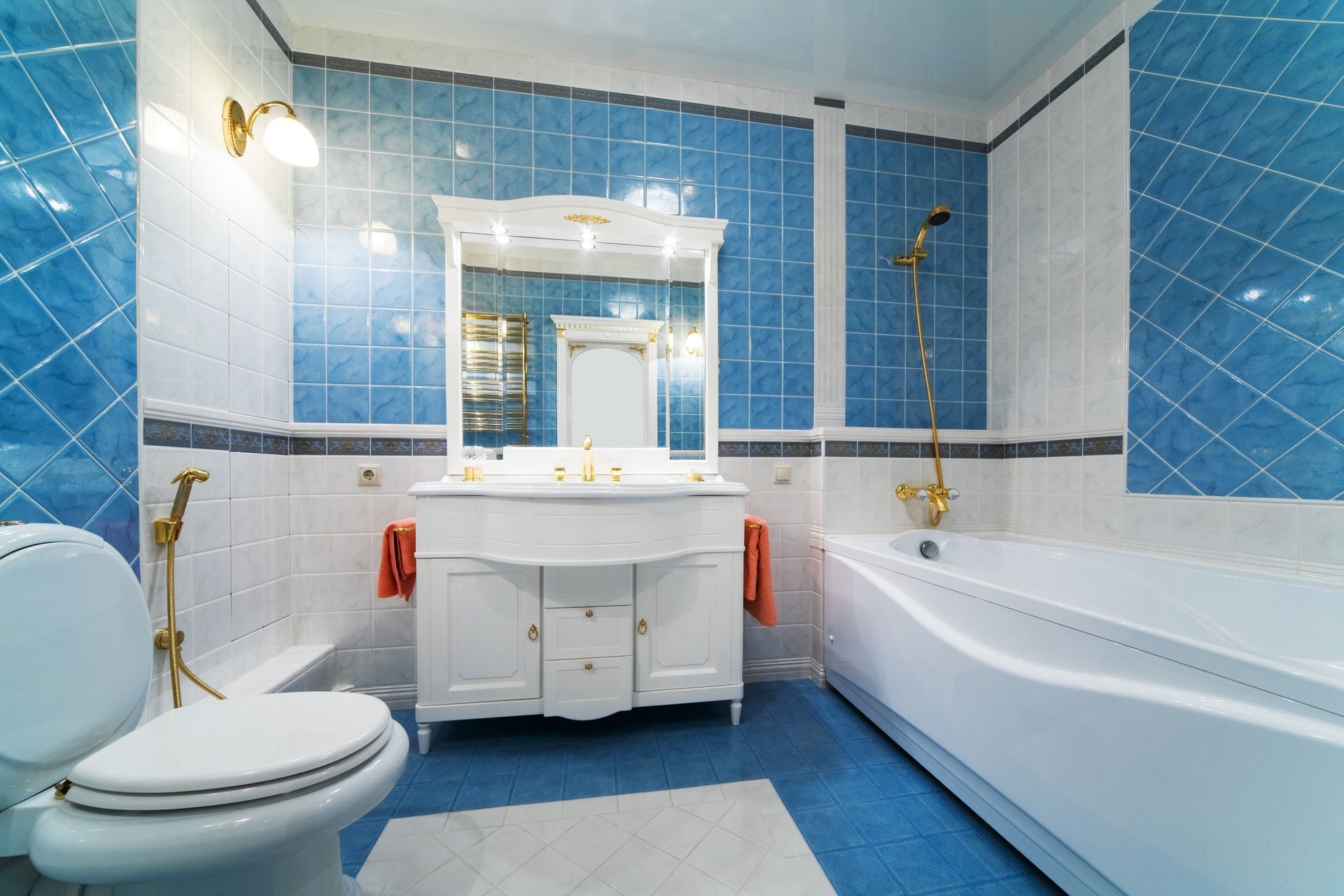 Blue and white bathroom with a toilet, vanit, tub, and blue tile.