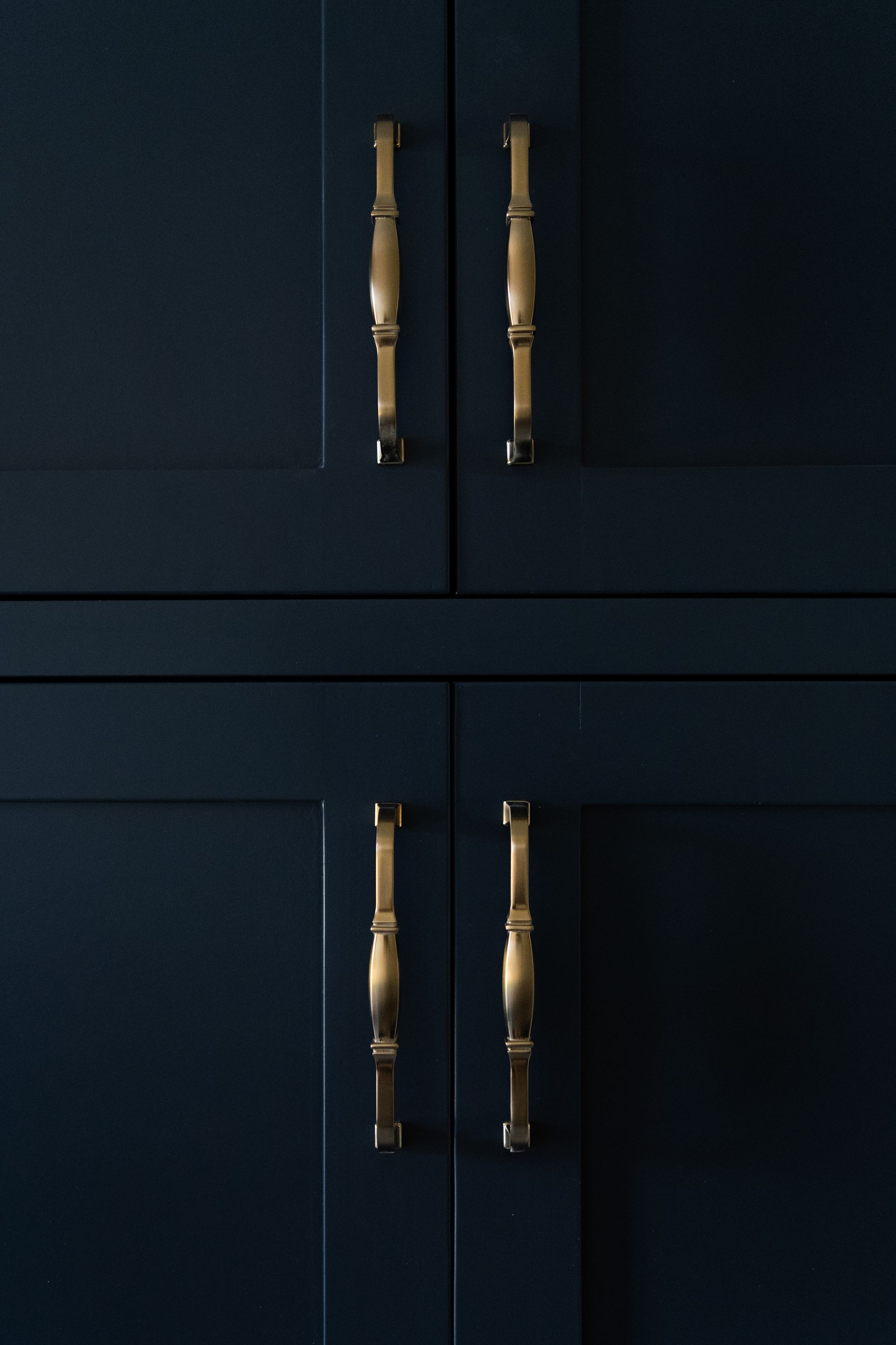 Dark cabinet doors with four brass handles arranged in a rectangular pattern.