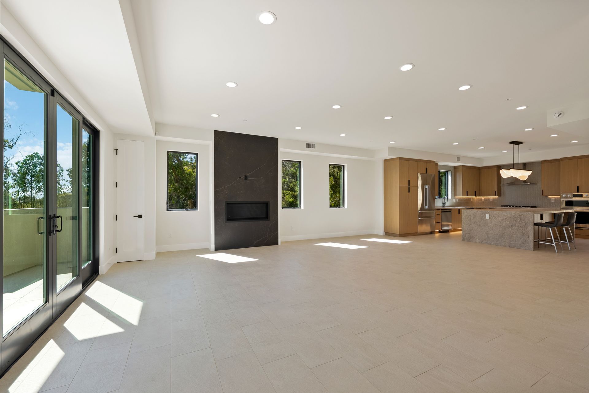 Bright open-concept living room with fireplace, large windows, and kitchen island.