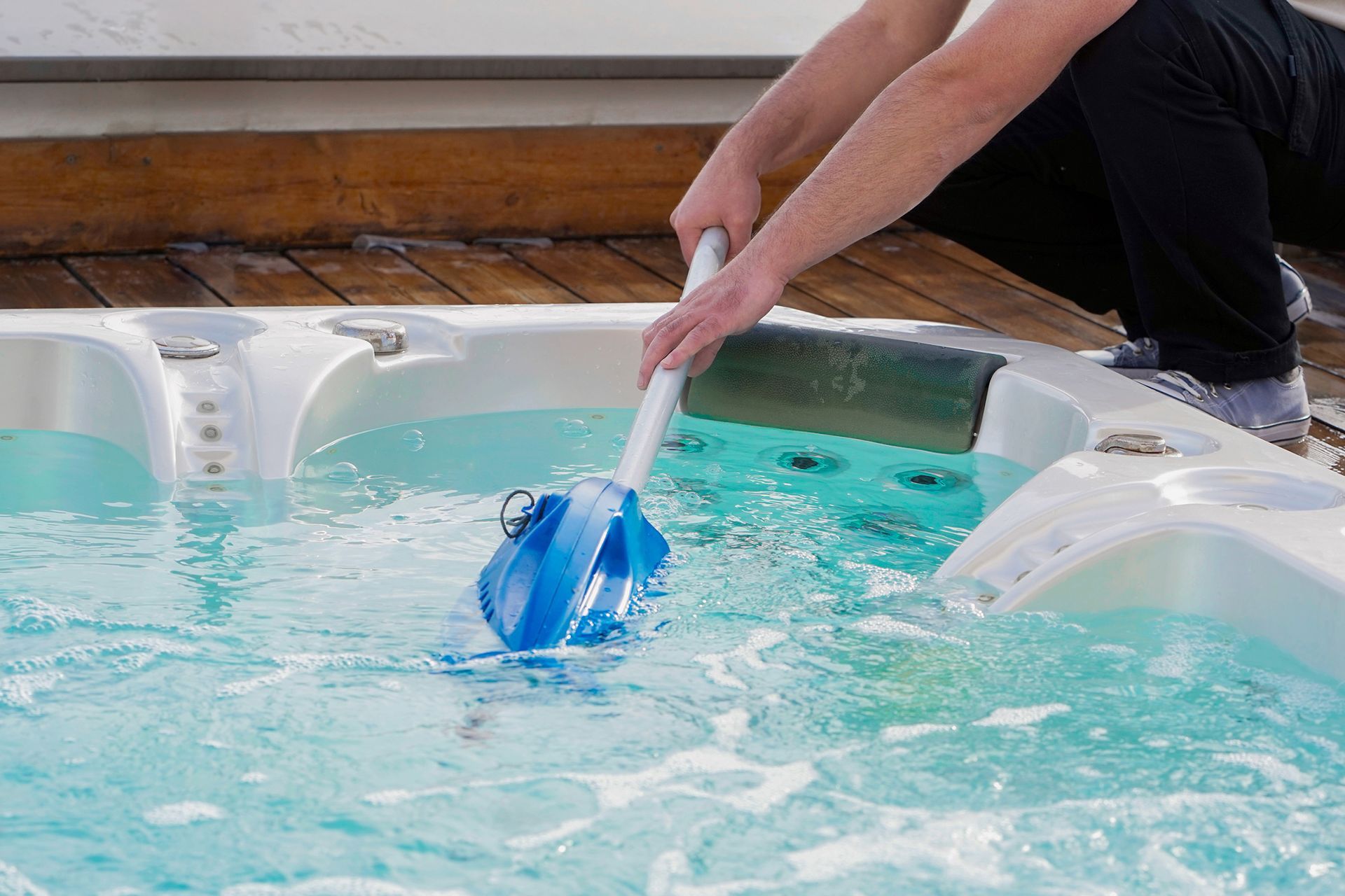 A person is cleaning a hot tub with a vacuum cleaner.