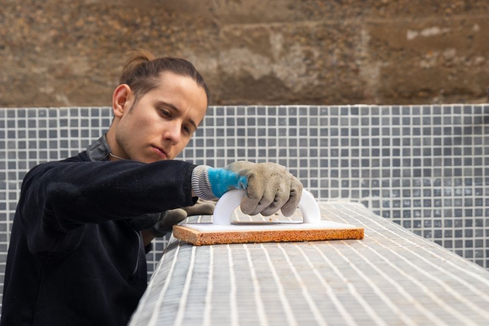 A man is working on a tile floor with a trowel.