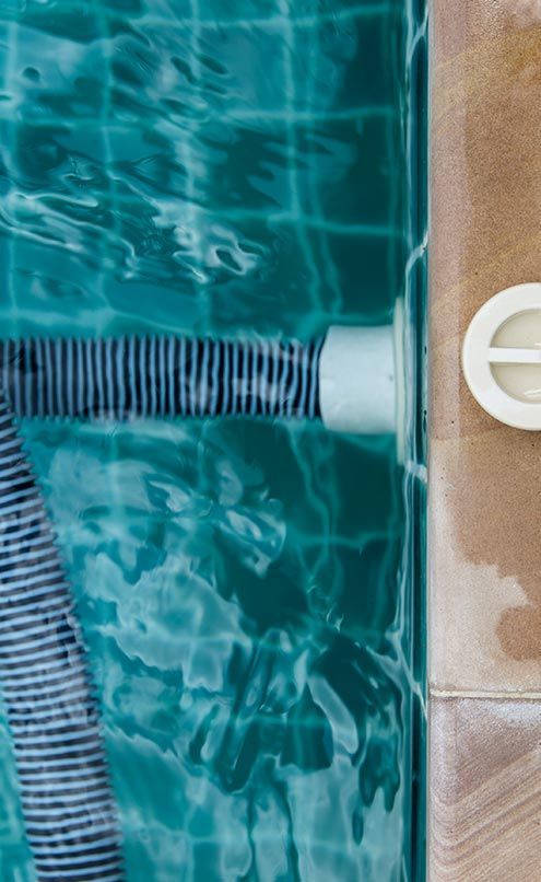 A hose is attached to the side of a swimming pool.