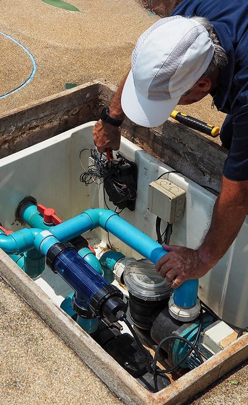 A man is working on a swimming pool pump.