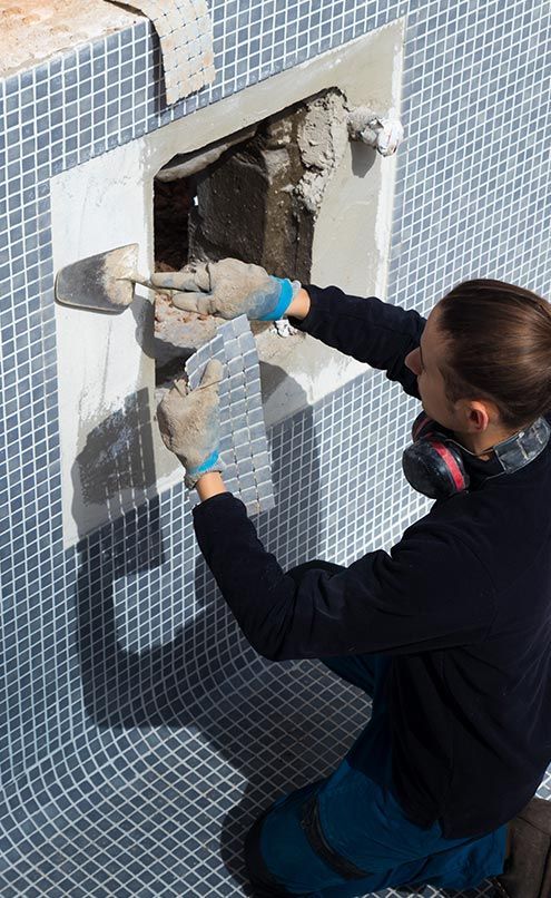 A man is working on a swimming pool wall.