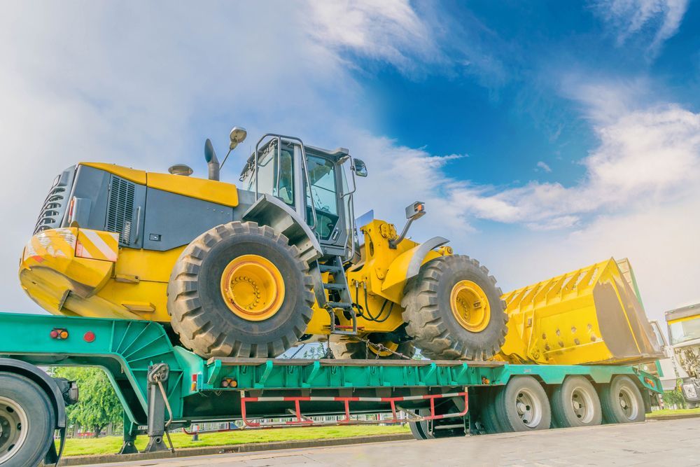 A Yellow Bulldozer is Sitting on Top of a Green Trailer — Hervey Bay Tilt Tray Hire In Tiaro, QLD
