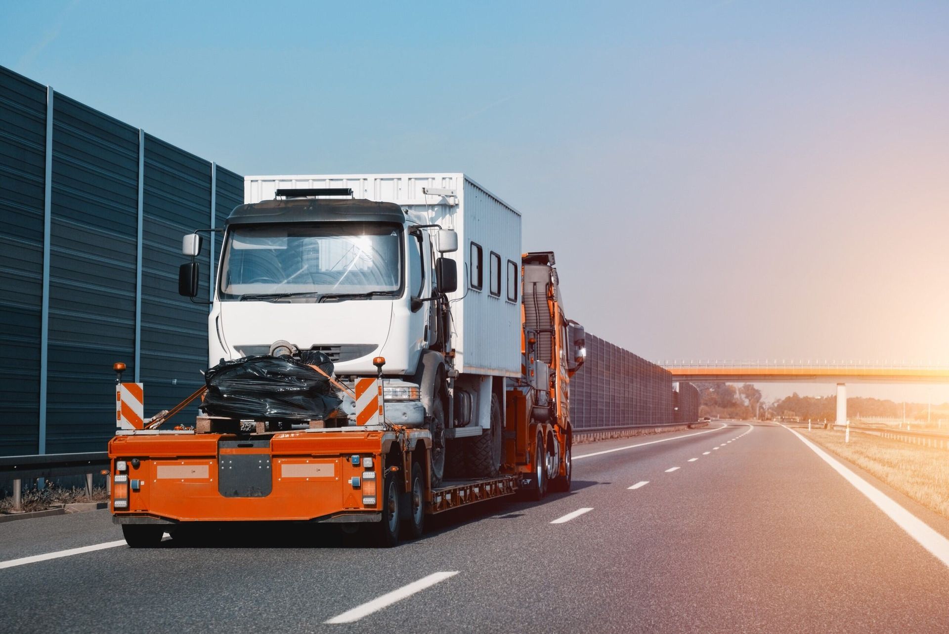 A White Truck is Driving Down a Highway With a Trailer Attached to It — Hervey Bay Tilt Tray Hire In Takura, QLD