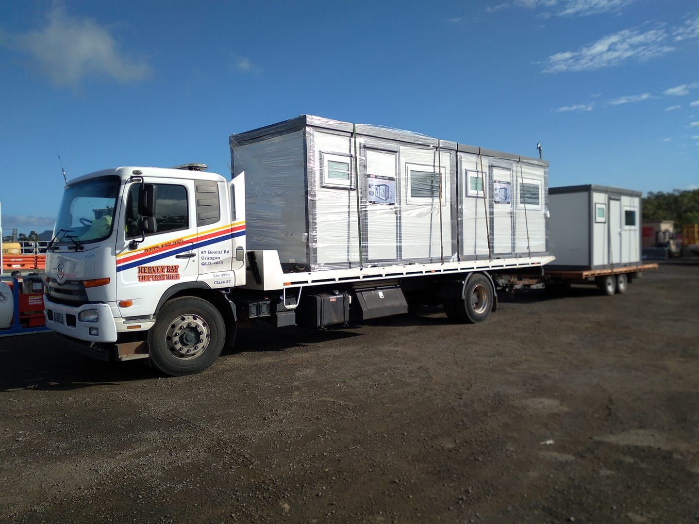 A Truck is Carrying a Trailer With a Bunch of Containers on It — Hervey Bay Tilt Tray Hire In Takura, QLD