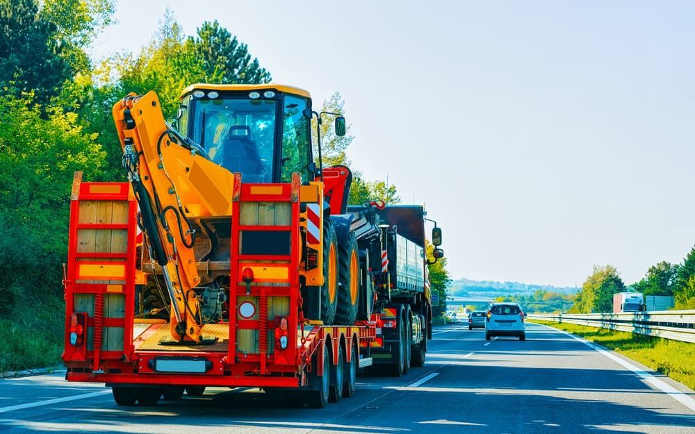 A Tractor is Driving Down a Highway on a Trailer — Hervey Bay Tilt Tray Hire In Takura, QLD