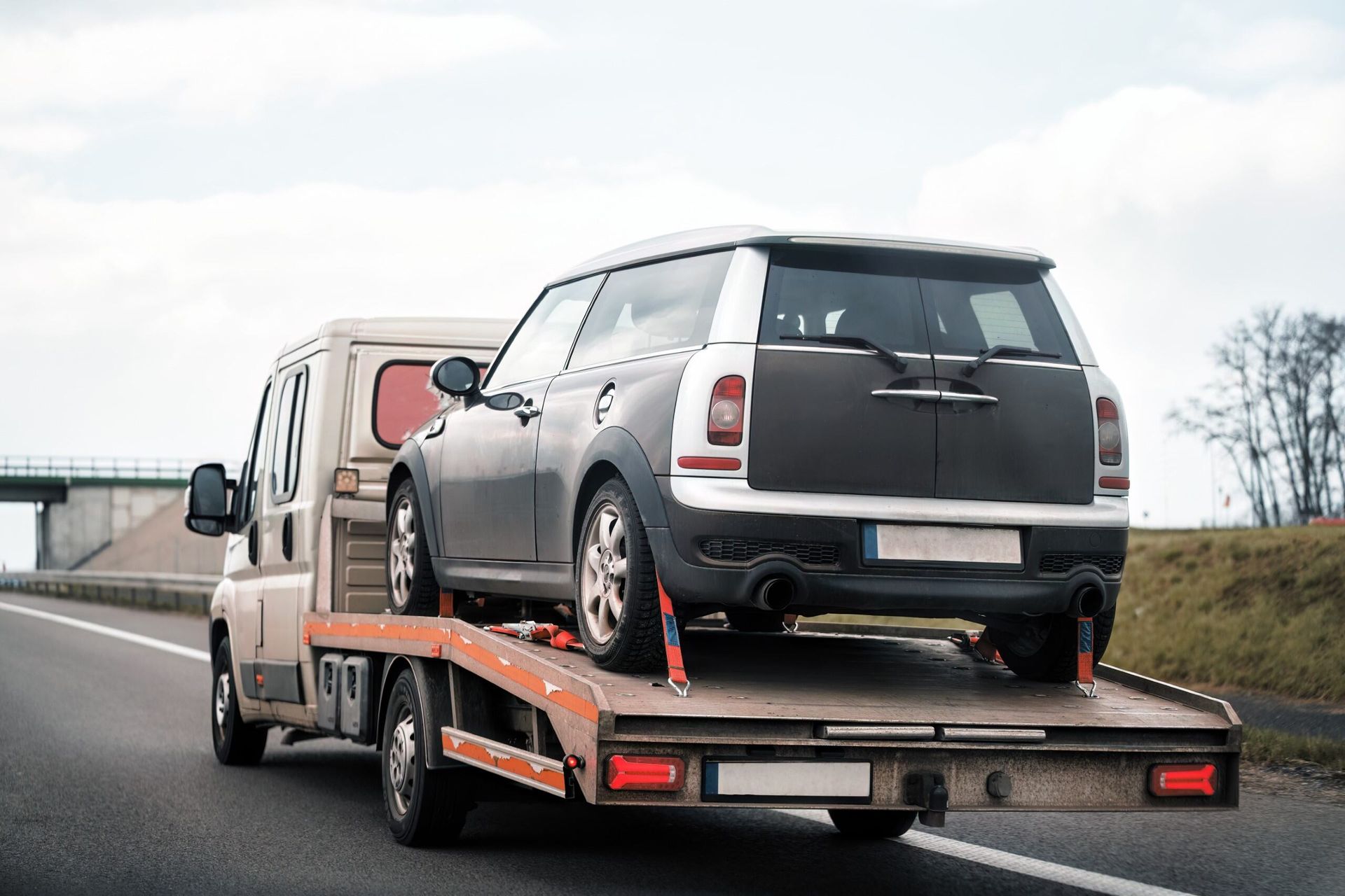 A Tow Truck is Towing a Car on a Highway — Hervey Bay Tilt Tray Hire In Maryborough, QLD