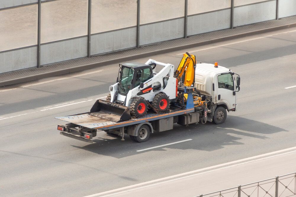 A Tow Truck is Carrying a Bulldozer on the Back of It — Hervey Bay Tilt Tray Hire In Bundaberg, QLD