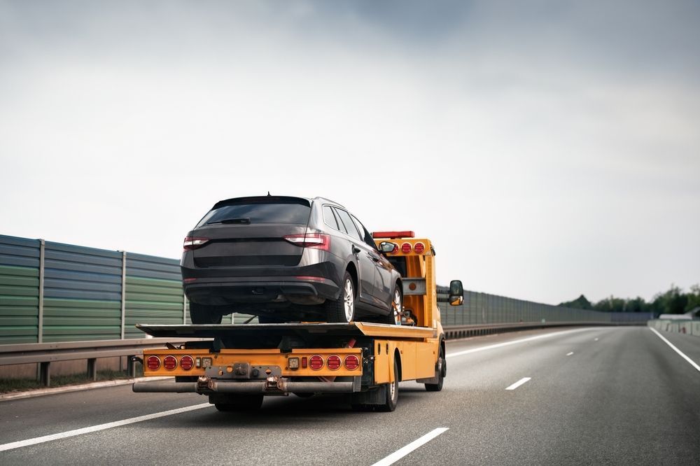 A Tow Truck is Towing a Car on the Highway — Hervey Bay Tilt Tray Hire In Maryborough, QLD