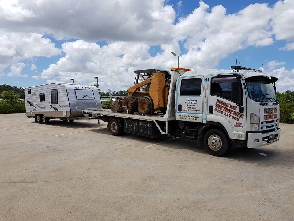 A Tow Truck is Towing a Trailer and a Bulldozer in a Parking Lot — Hervey Bay Tilt Tray Hire In Takura, QLD